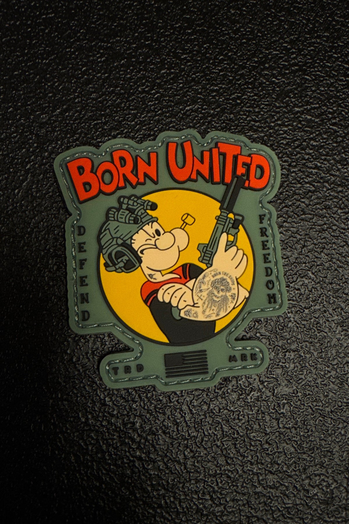 Patch with cartoon character and 'Born United' text on a textured black background