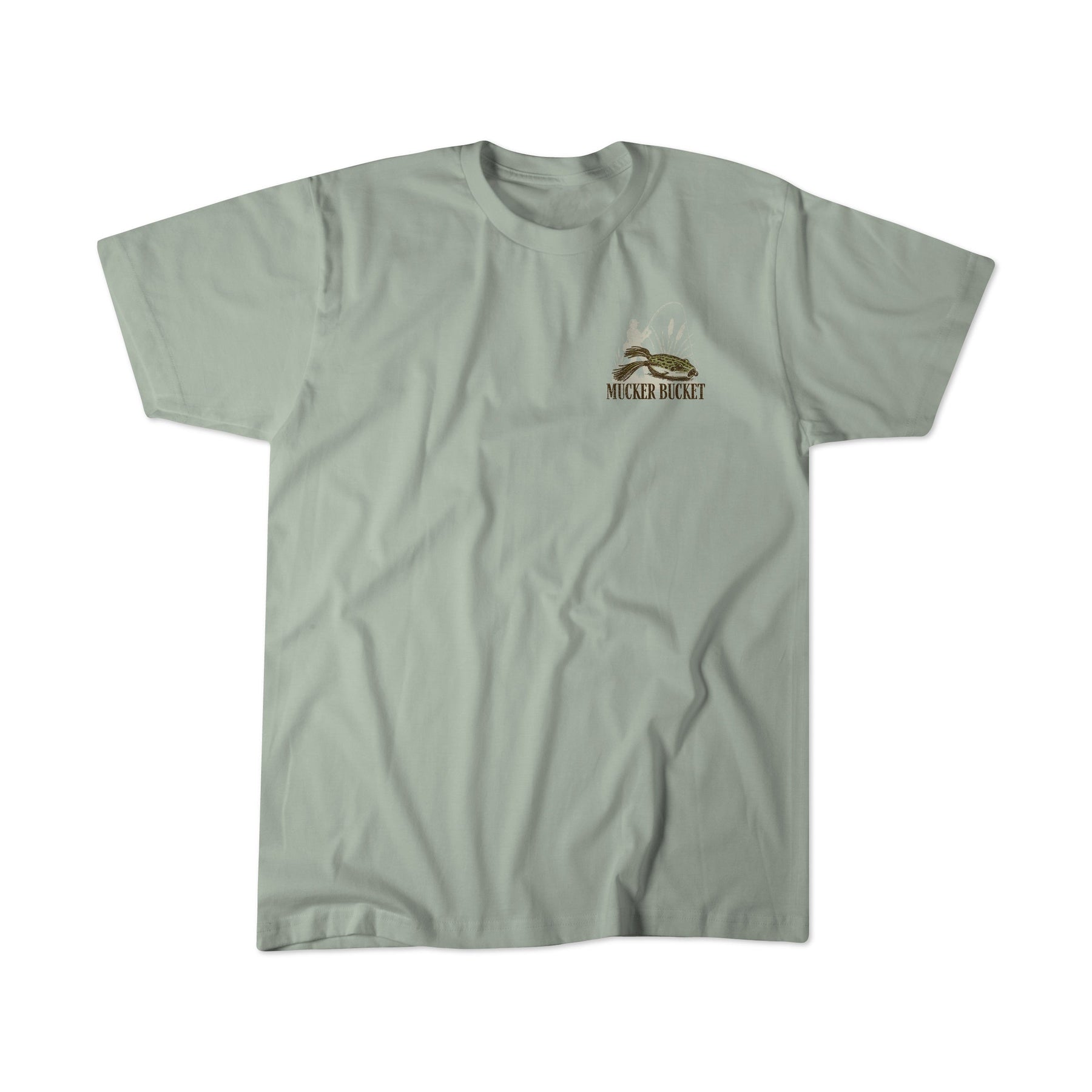 The Bait DNA Premium Tee by Mucker Bucket is a light gray, premium relaxed fit t-shirt featuring a small Mucker Bucket logo and mountain graphic on the left chest. Made from soft ring-spun cotton, this tee is shown laid flat with visible fabric creases, emphasizing its comfortable quality.