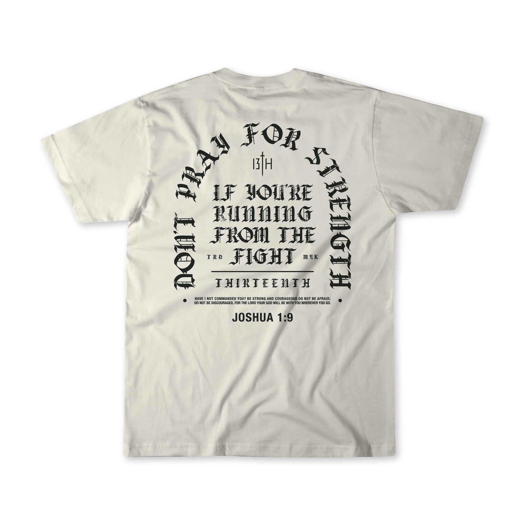Introducing the Be Strong Premium Tee by 13th—a white, high-quality shirt featuring bold black gothic-style text on the back: “Don’t pray for strength if you’re running from the fight,” referencing Joshua 1:9. This powerful statement piece is a standout addition to our faith apparel collection.