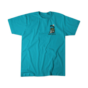 The Shallows by Born United Private Label is a bright turquoise t-shirt featuring a small chest graphic of two palm trees, a sun, and a bear with a surfboard, plus BORN UNITED text below. Shirt shown laid flat on white background.