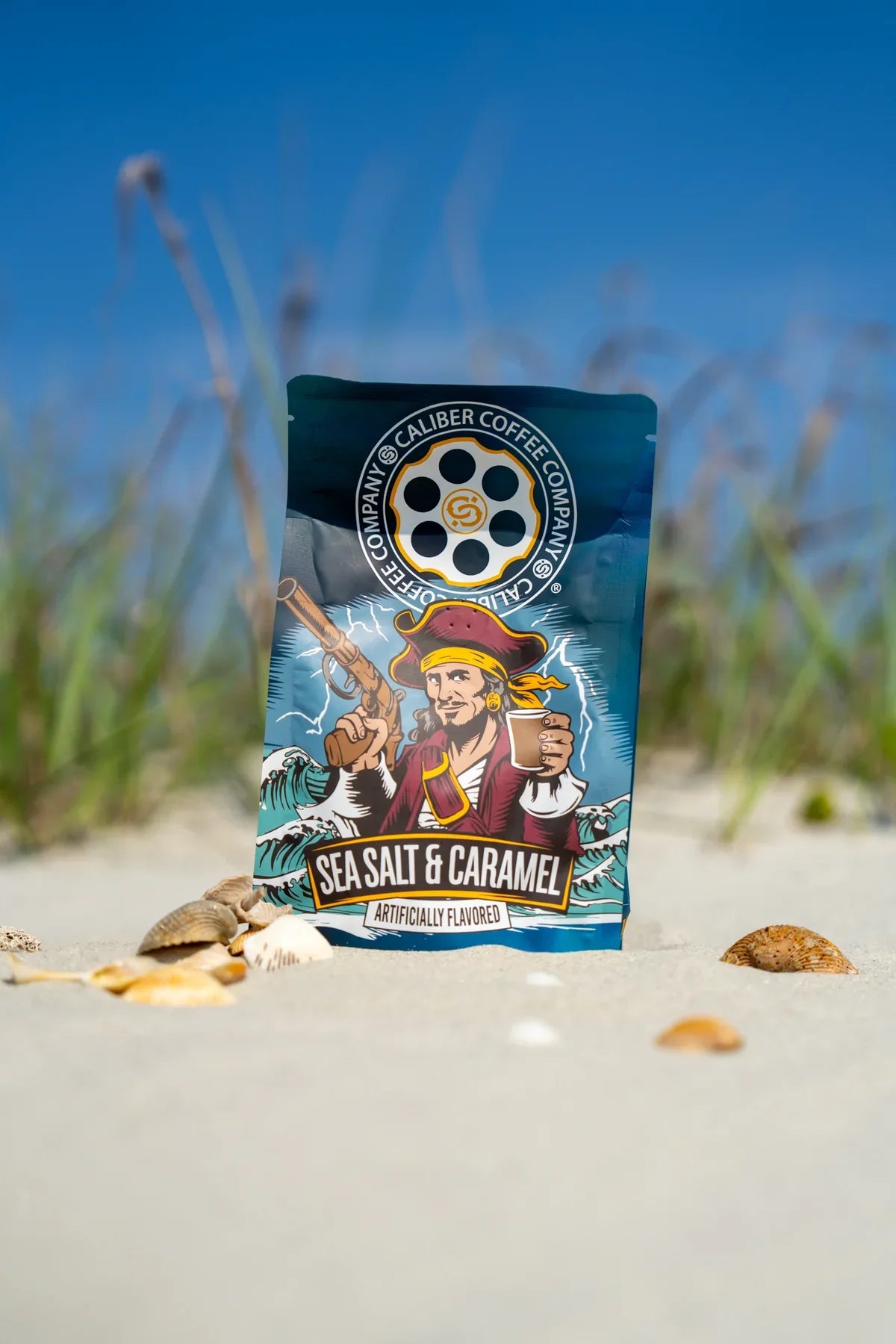 A bag of Caliber Sea Salt & Caramel - Ground coffee featuring an illustration of a pirate standing on a sandy beach.