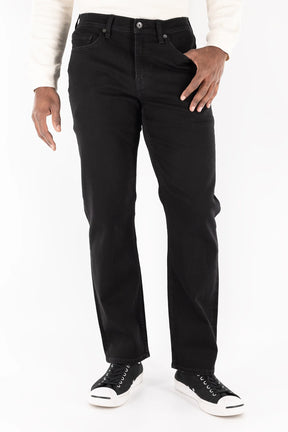 A person wears a white long-sleeve shirt, Devil Dog Dungarees Relaxed Straight Jean - Cornelius, and black sneakers with white soles, standing against a plain white background. The image is cropped from the shoulders down.
