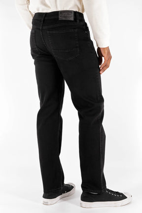 Wearing Devil Dog Dungarees Relaxed Straight Jean - Cornelius in black, a person stands with their back to the camera, paired with a white sweater and black-and-white sneakers against a plain white background.