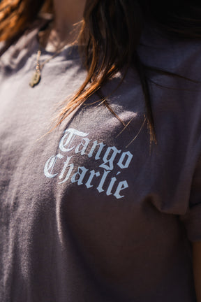Gray short-sleeve Lift Heavy. Praise Hard. Shiitake Tee by Tango Charlie Apparel with the text Tango Charlie and the mantra Praise Hard, Lift Heavy printed in white on the chest.