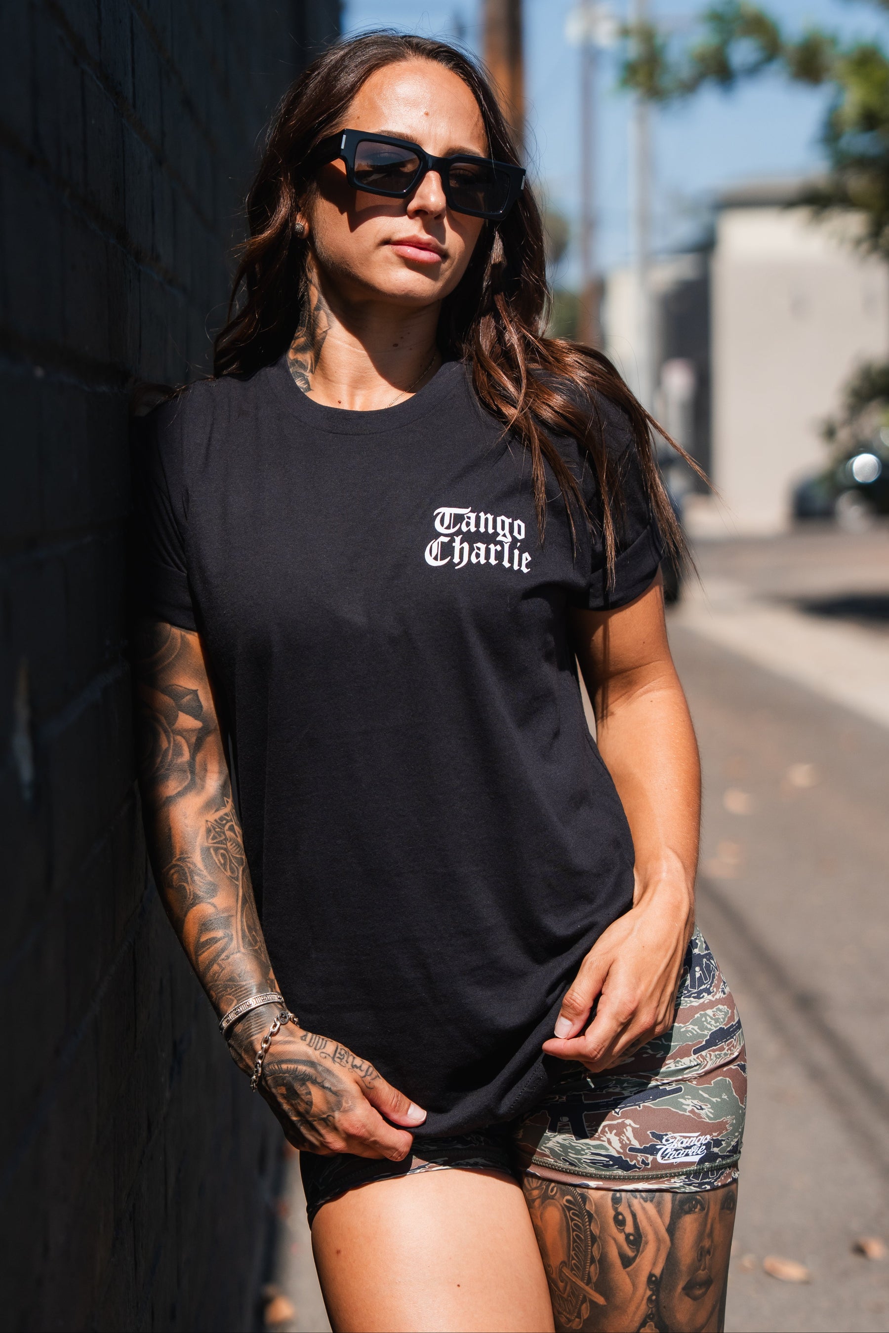 A woman wearing black sunglasses and a black Lift Heavy. Praise Hard. Black Tee by Tango Charlie Apparel, ready to praise hard and lift heavy.
