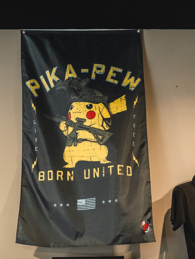 The Pika-Pew Flag by Born United Private Label features Pikachu as a tactical soldier with a rifle, yellow "PIKA-PEW BORN UNITED" and "LIVE FREE" text on the sides, and an American flag at the bottom. Black background.