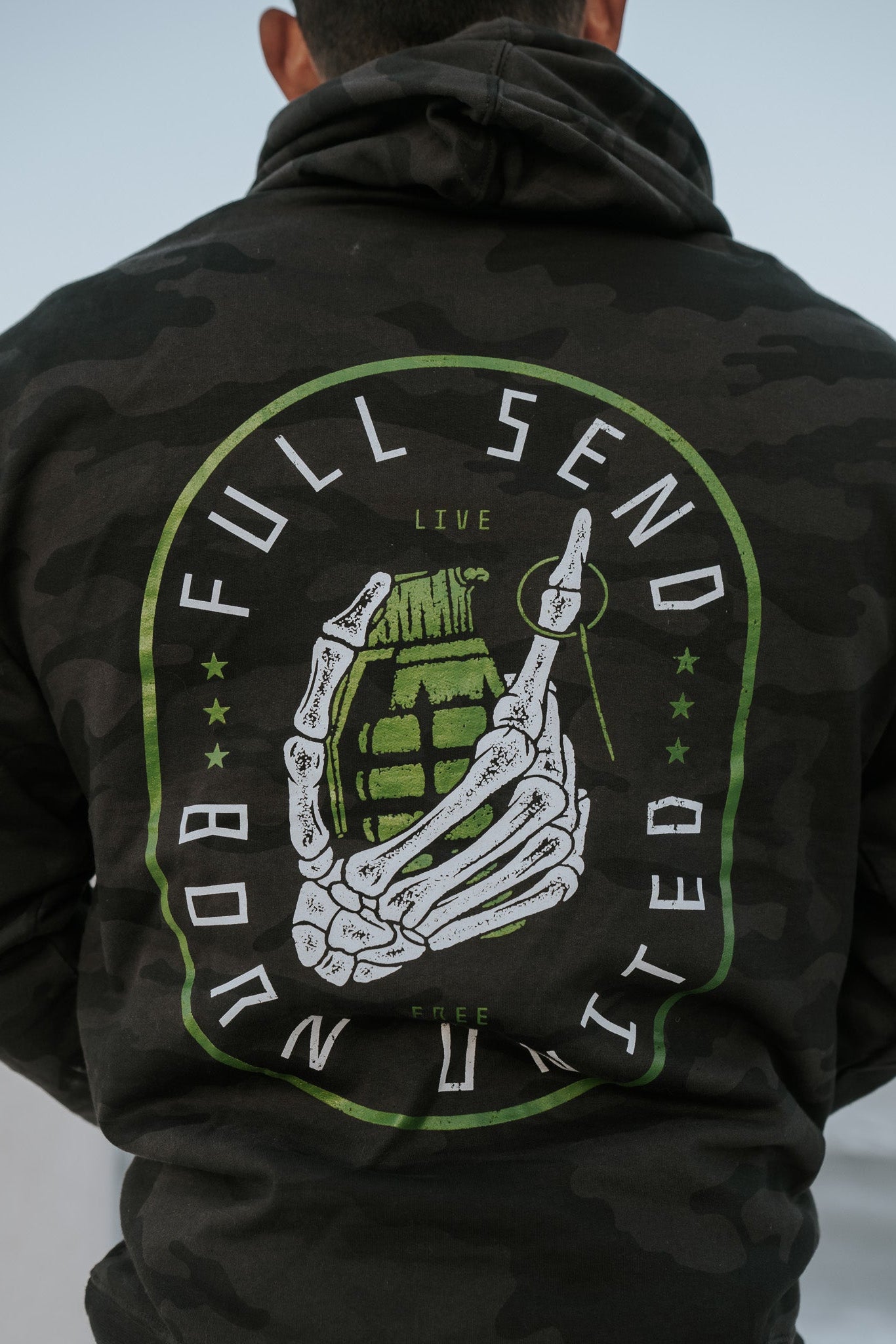 Wearing the Full Send Camo Hoodie by Born United Private Label, featuring a skeleton hand clutching a grenade with FULL SEND and BORN UNITED, embodies the bold Full Send spirit.