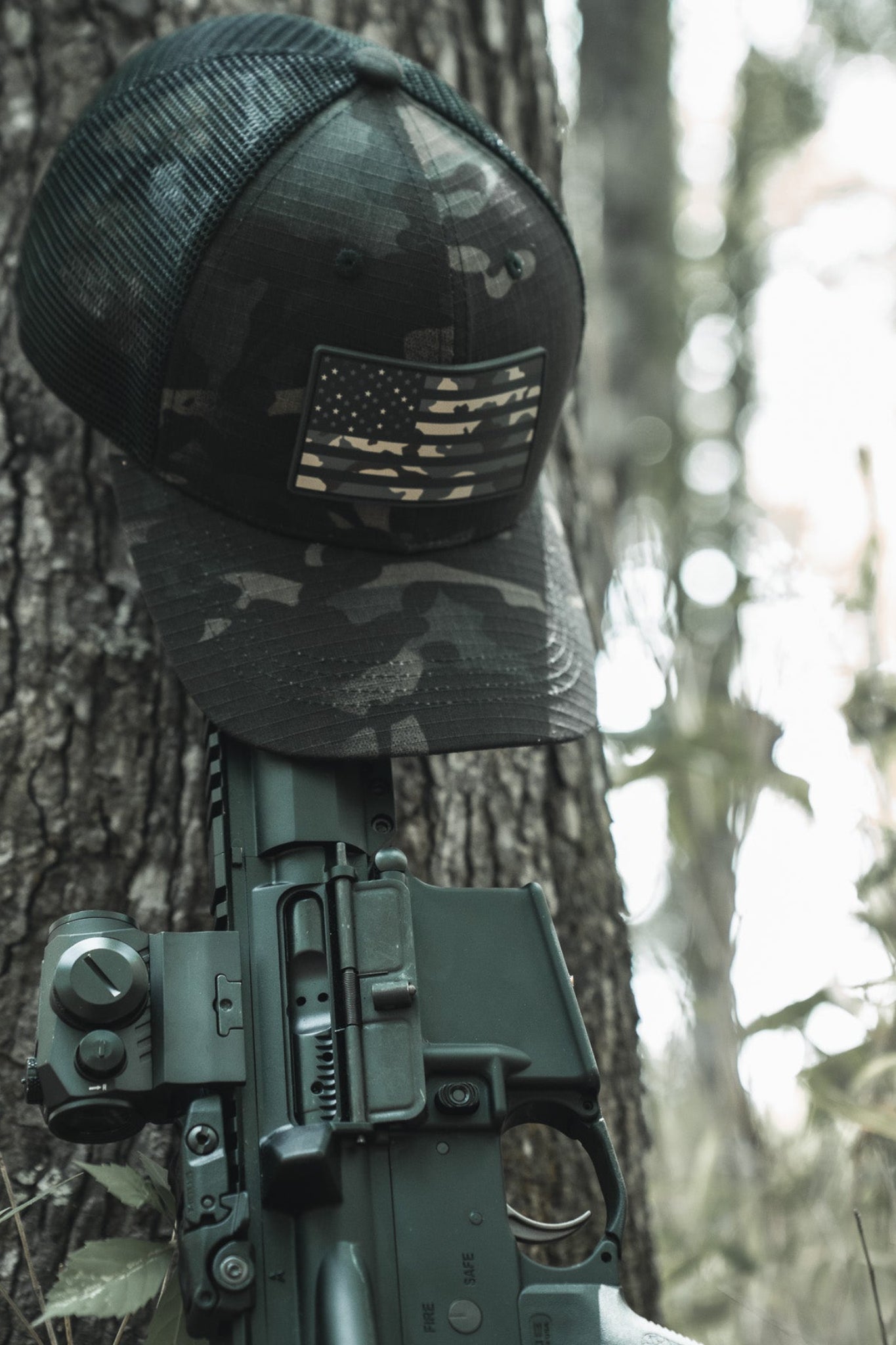 Camouflage helmet with American flag patch on a rifle against a forest background