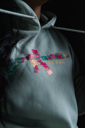 Feral - Premium Dusty Sage Hoodie in sage green, featuring a tropical floral rifle graphic and FERAL printed on the chest.