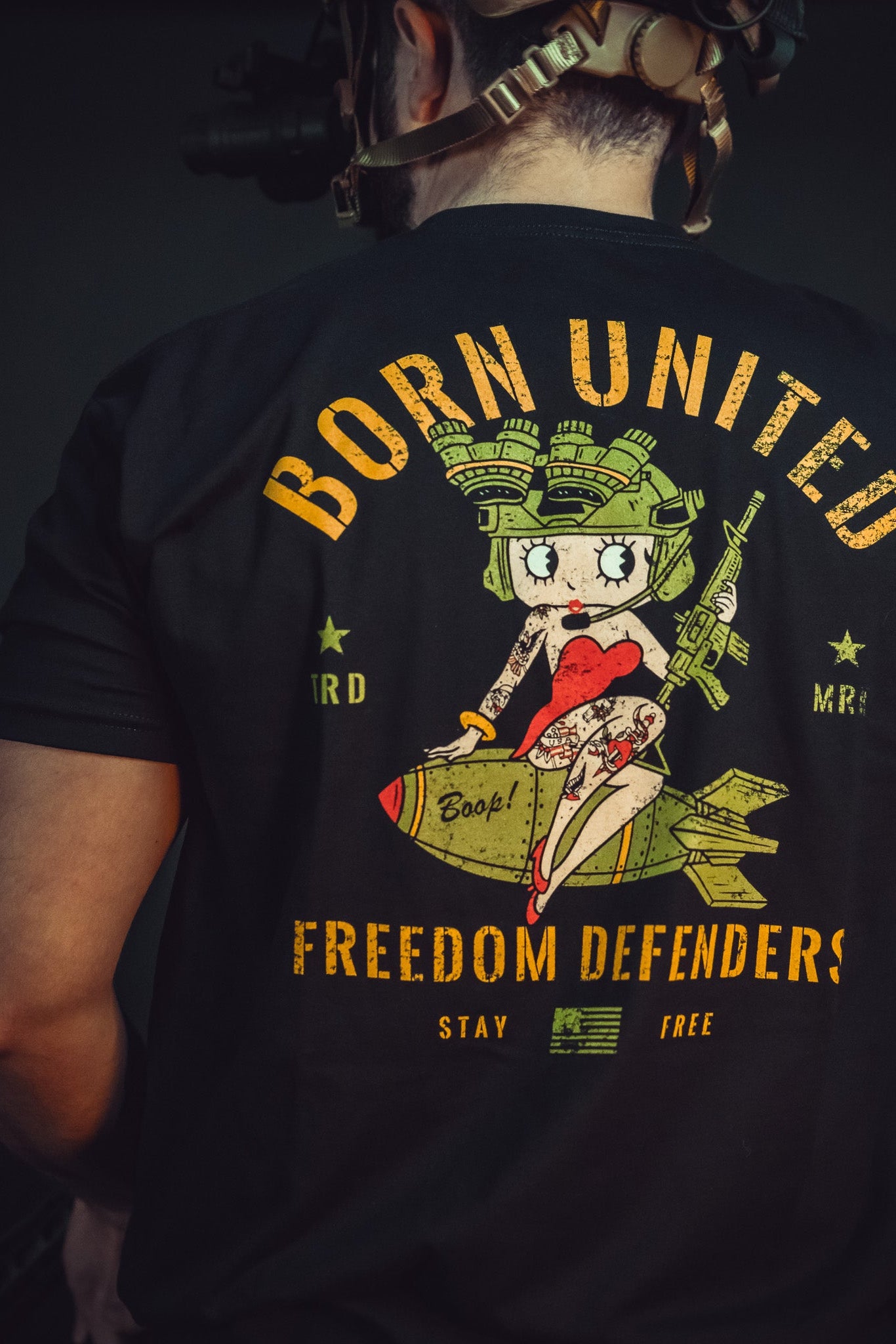 A person in a Born United Betty Boop Tee, featuring a cartoon character on a bomb, displays the phrases Born United, Freedom Defenders, and Stay Free, boldly conveying their commitment to defending freedom.