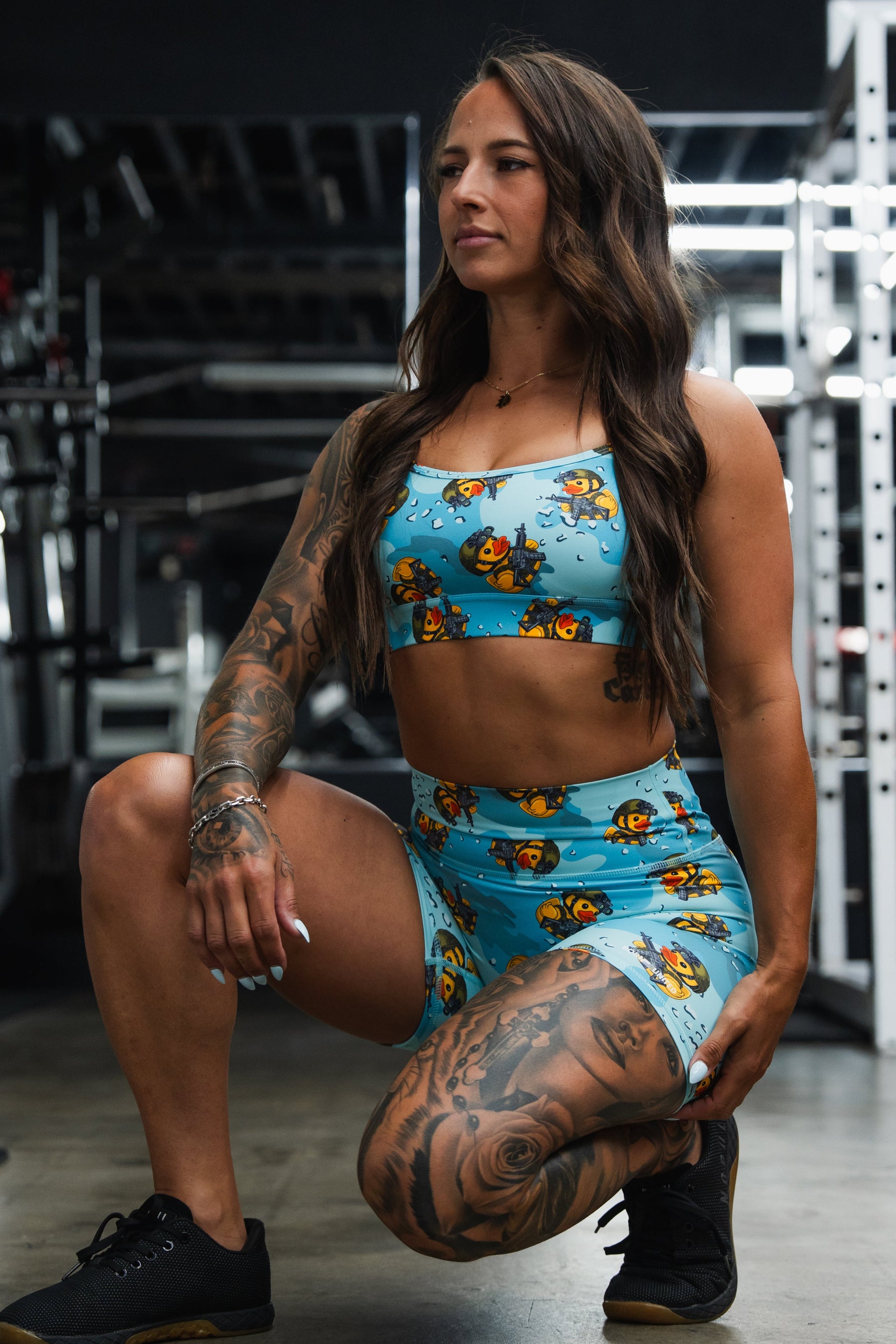 Woman in a blue patterned sports outfit posing in a gym.