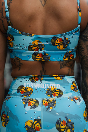 Close-up of a woman's back in Born United Private Label "Tacti-Quack" high-waisted seamless front compression training shorts, sports bra, and leggings, all featuring cartoon military ducks and "BORN UNITED" printed on the bra and leggings.