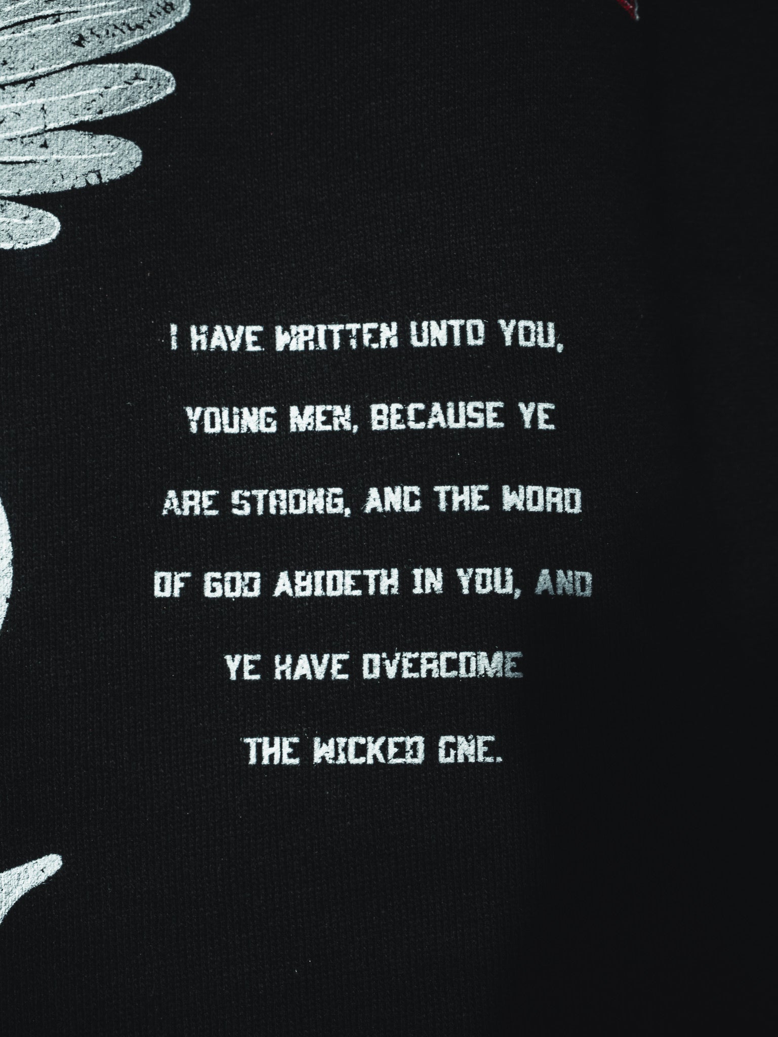 The 13th Overcome Premium Hoodie features white text on black: "I have written unto you, young men, because ye are strong..." (John 2:14), with partial white feather designs on the left.