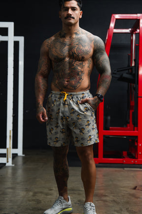 Muscular man in a gym wearing patterned shorts and sneakers.