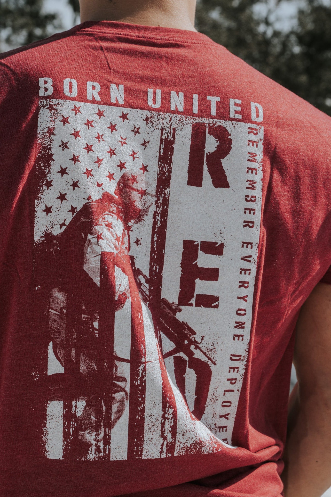 Wearing the R.E.D. Friday red shirt from Born United Private Label showcases a stylized American flag and soldier design featuring BORN UNITED and RED, which stands for Remember Everyone Deployed, honoring the brave soldiers who defend our freedoms.