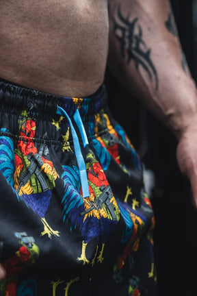 Colorful patterned shorts with a tattoo on a person's arm against a dark background