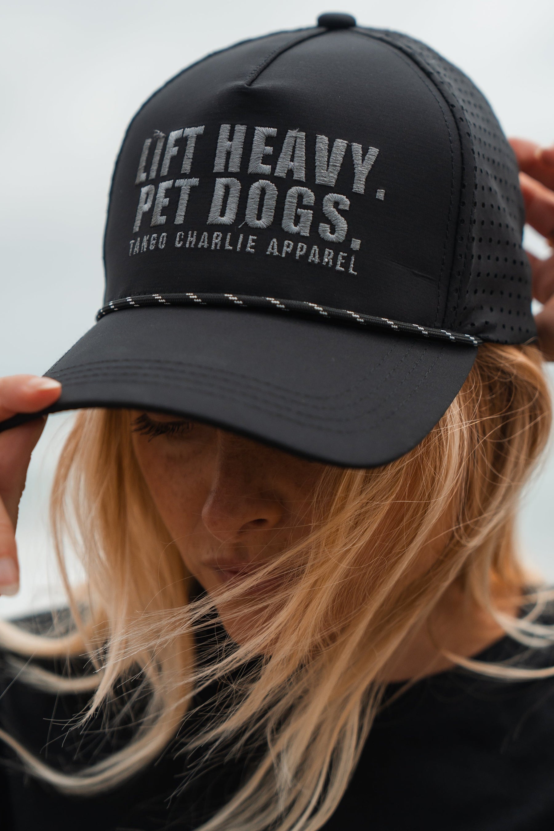 Person wearing a black cap with 'Lift Heavy Pet Dogs' text, blurred background