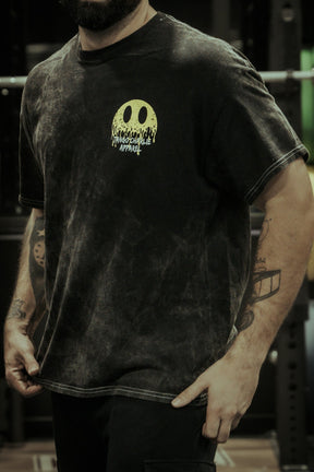 A person wearing a faded black Unleash The Savage Premium Tee by Tango Charlie Apparel stands in a gym. Savage tattoos show on their forearms, adding edge to this authentic piece.