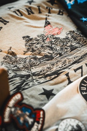 A close-up of the Born United Patriot Box Limited Edition Tee by Born United Private Label, inspired by Iwo Jima with soldiers raising the flag, star and patch designs—ideal for America's 250th Birthday celebration.