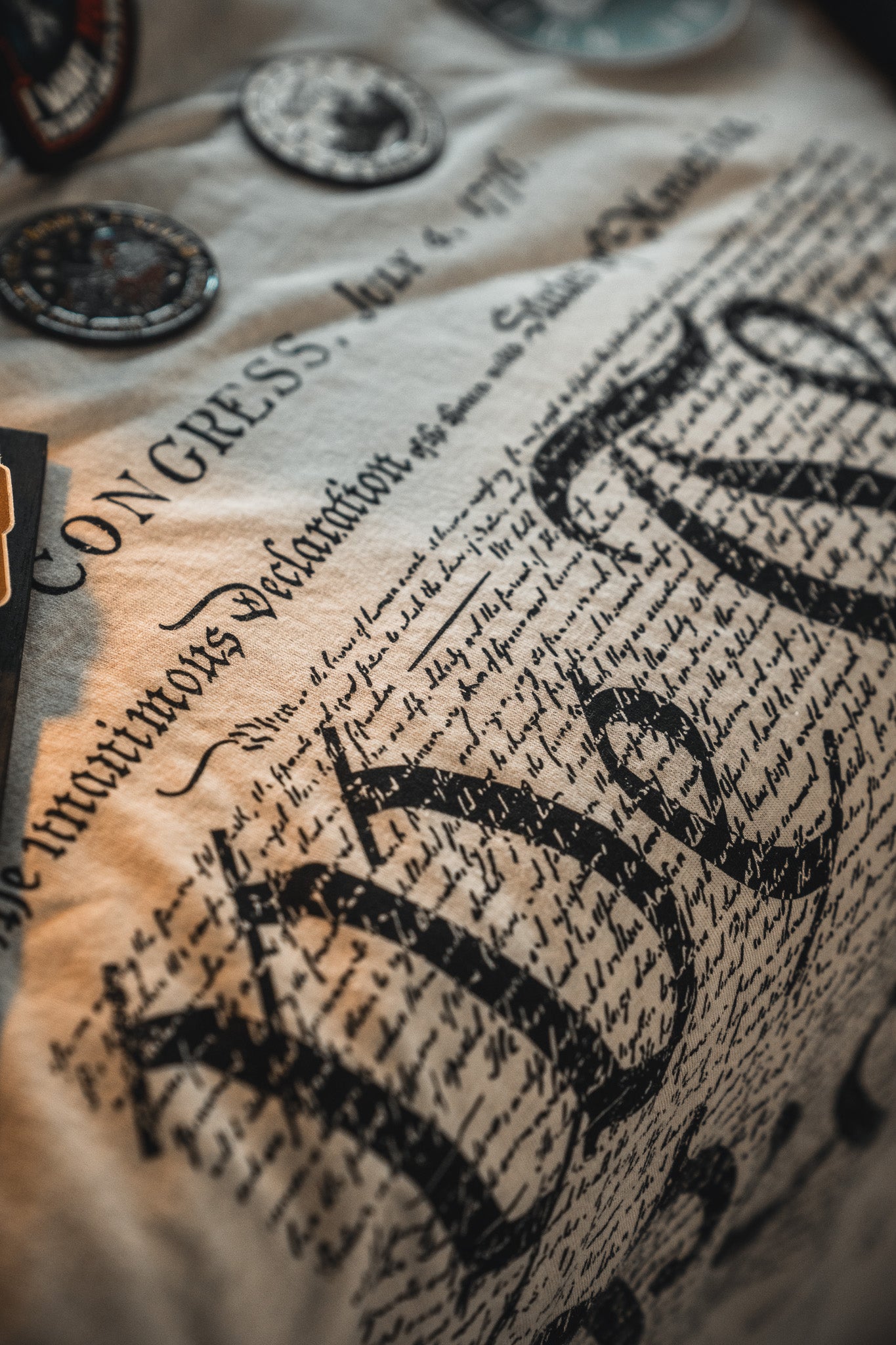 Close-up of fabric printed with the U.S. Declaration of Independence in decorative script, plus commemorative patches—perfect for America's 250th or adding to your Born United Patriot Box by Born United Private Label.