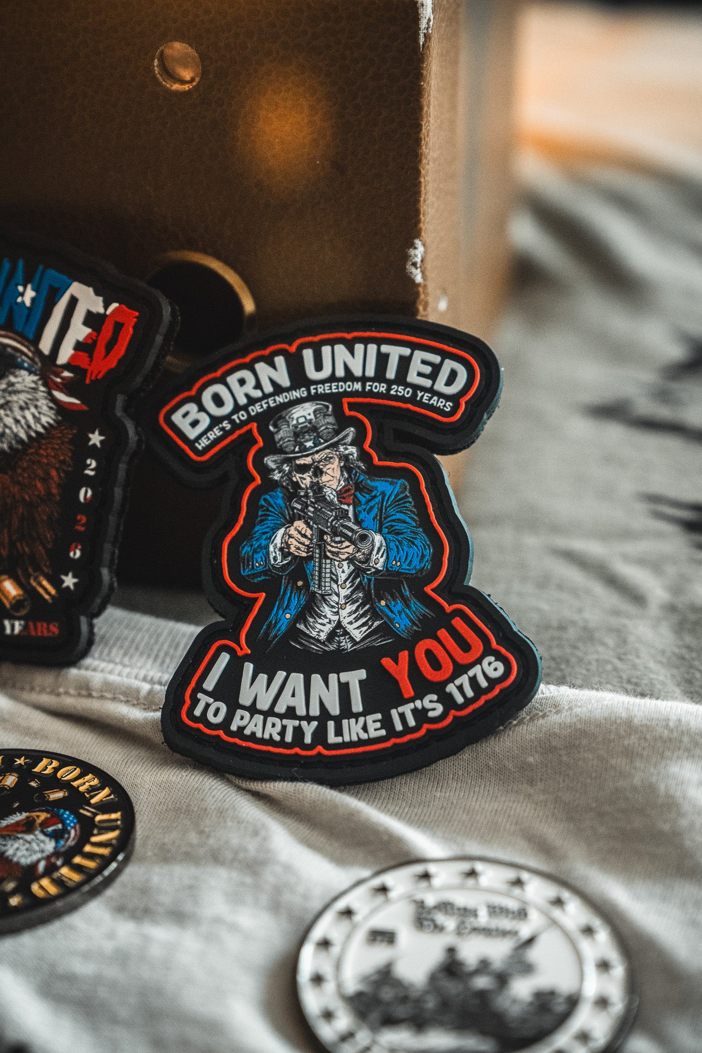 The Born United Patriot Box by Born United Private Label includes a patch for America’s 250th Birthday featuring Uncle Sam, “BORN UNITED—HERE TO DEFEND FREEDOM FOR 250 YEARS—I WANT YOU TO PARTY LIKE ITS 1776,” plus other patches and a coin.