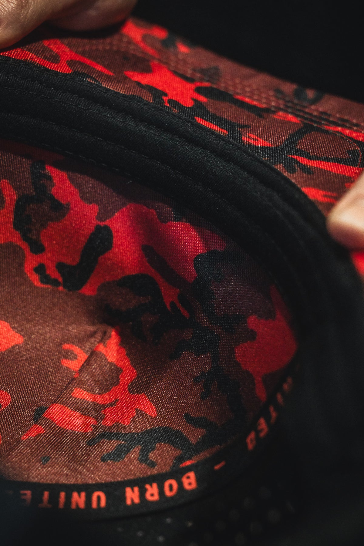 Close-up of a product with red and black camouflage pattern and 'Born United' branding.