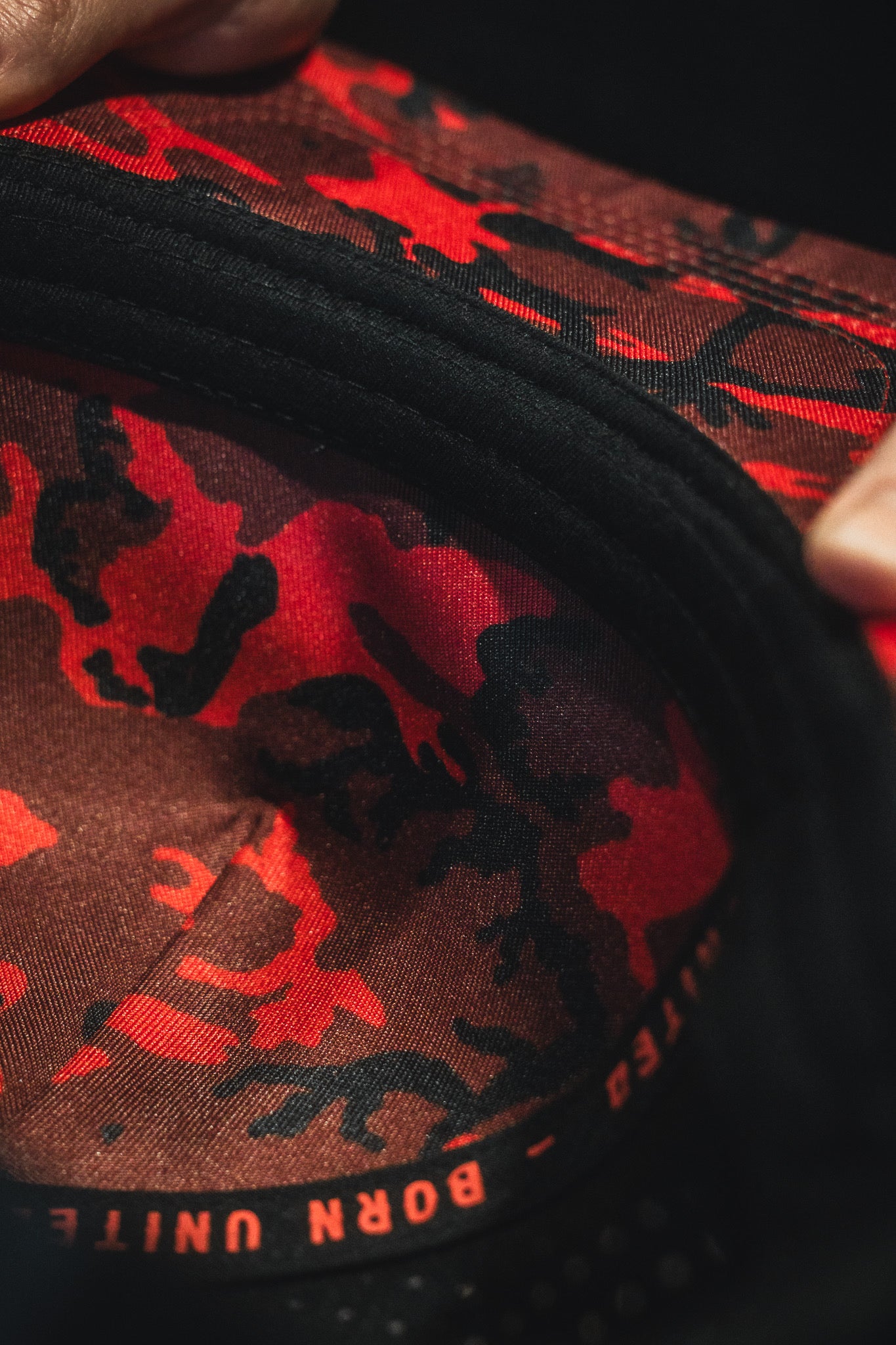 Close-up of a product with red and black camouflage pattern and 'Born United' branding.