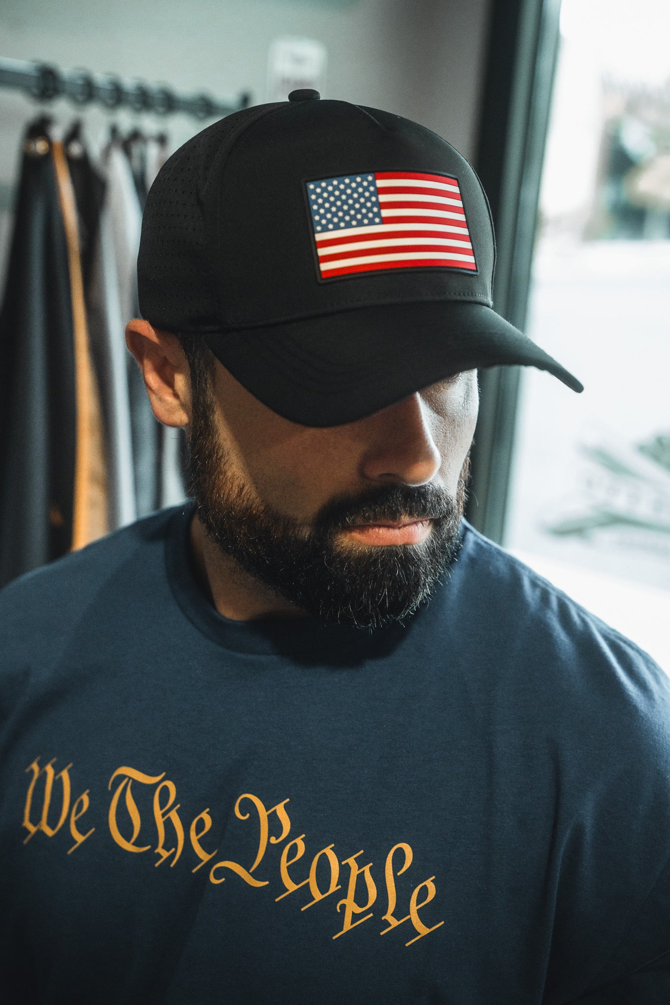 Man wearing a black cap with an American flag and a 'We The People' shirt.
