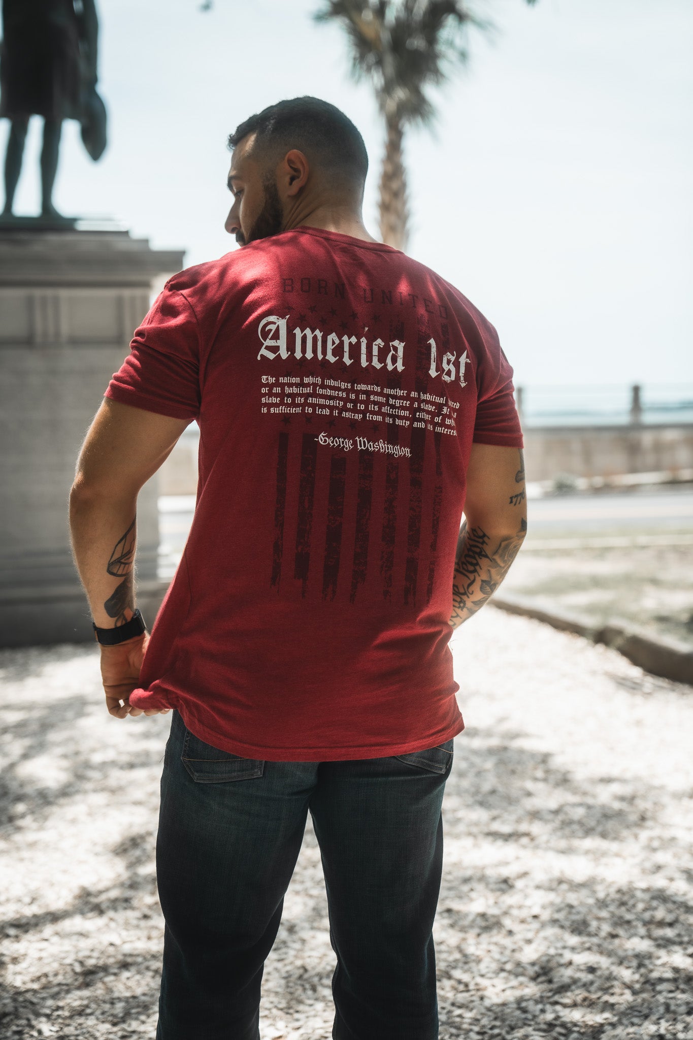 Man wearing a red t-shirt with text on the back, standing outdoors.
