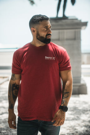 Man wearing a red t-shirt with text, standing outdoors.