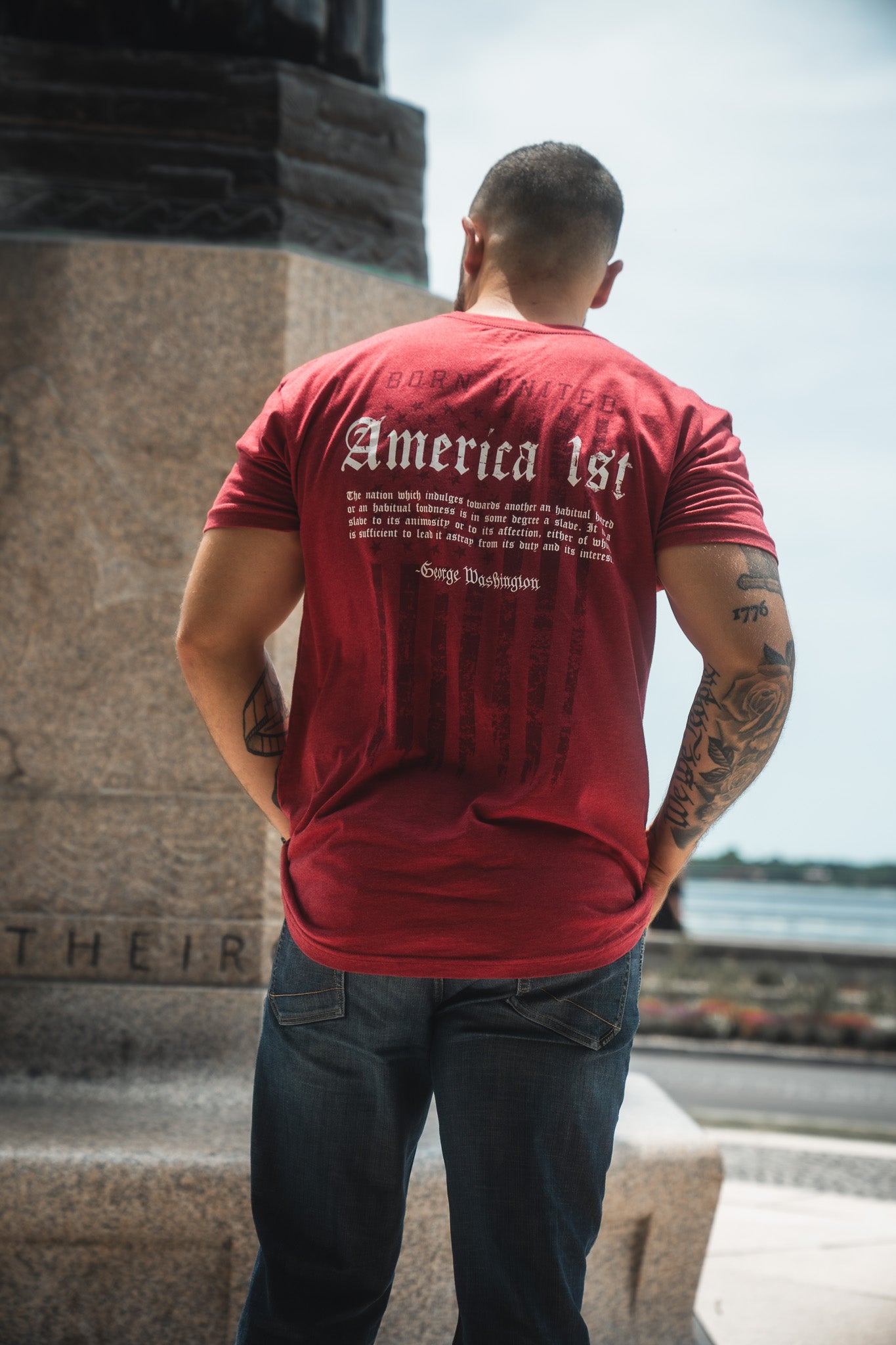 Person wearing a red t-shirt with text on the back, standing outdoors.
