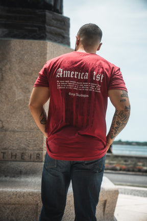Person wearing a red t-shirt with text on the back, standing outdoors.