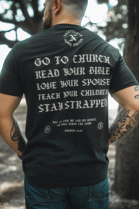 A person stands outdoors in a Born United Private Label Kingdom Protector Premium Tee featuring “GO TO CHURCH, READ YOUR BIBLE, LOVE YOUR SPOUSE, TEACH YOUR CHILDREN, STAY STRAPPED" with Joshua 24:15—ideal for Christian home decor or wall art inspiration.