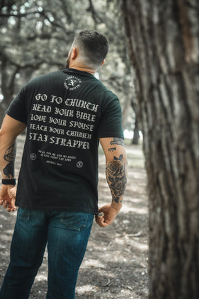 A man stands outdoors with his back to the camera, wearing the Kingdom Protector Premium Tee by Born United Private Label—its white text of life advice reminiscent of inspirational Christian home decor like Joshua 24:15 wall art.