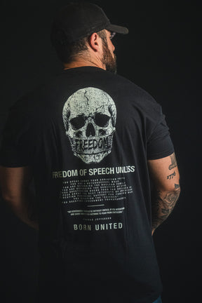 A man stands against a dark background, showcasing his right arm tattoos while wearing the Born United Private Label "Freedom of Speech" T-shirt—a bold statement of personal beliefs and free expression.
