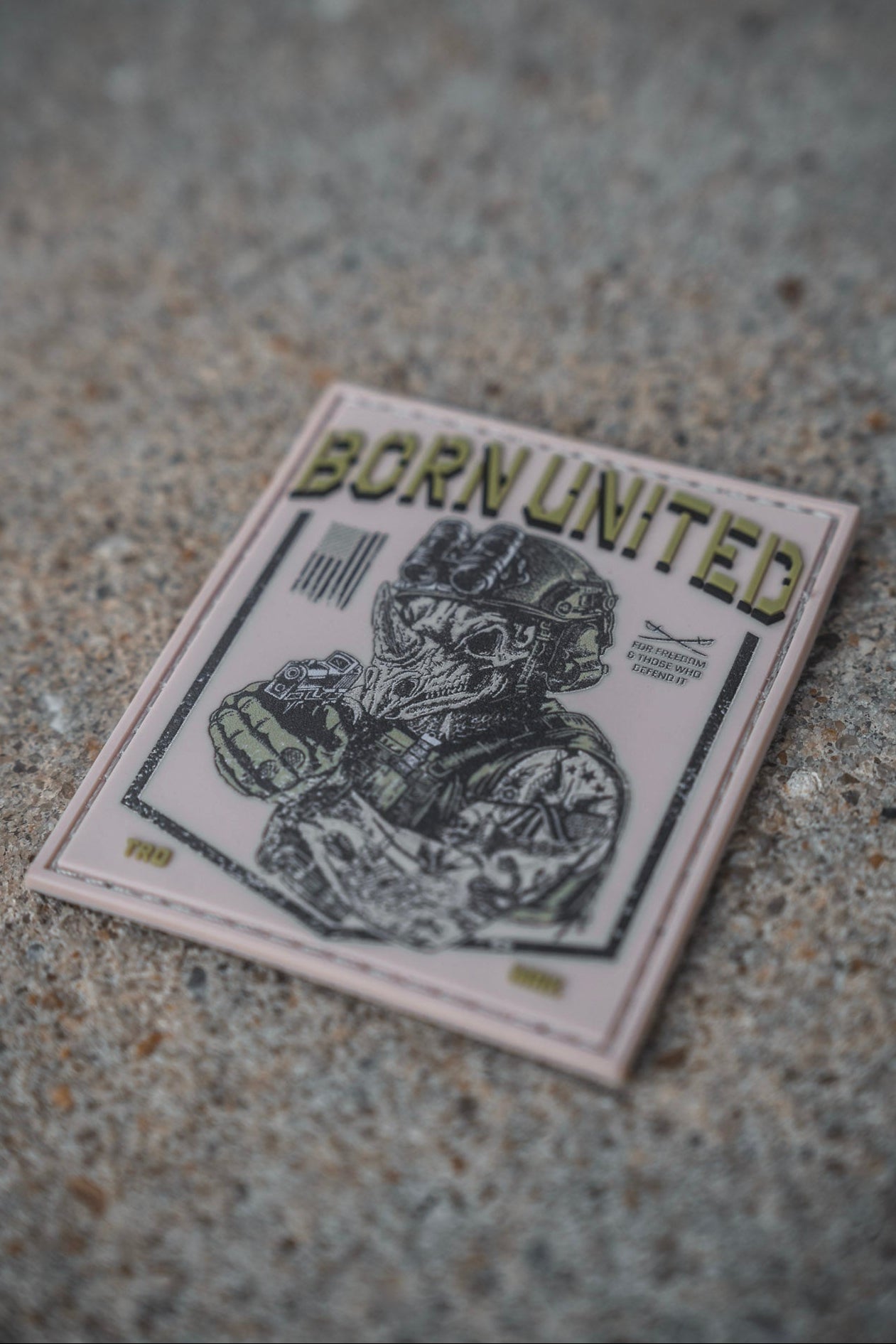 A 3x3 inch square TacRhino PVC patch from Born United Private Label, designed for Velcro attachment on concrete, features a helmeted soldier graphic and the text "BORN UNITED" at the top.
