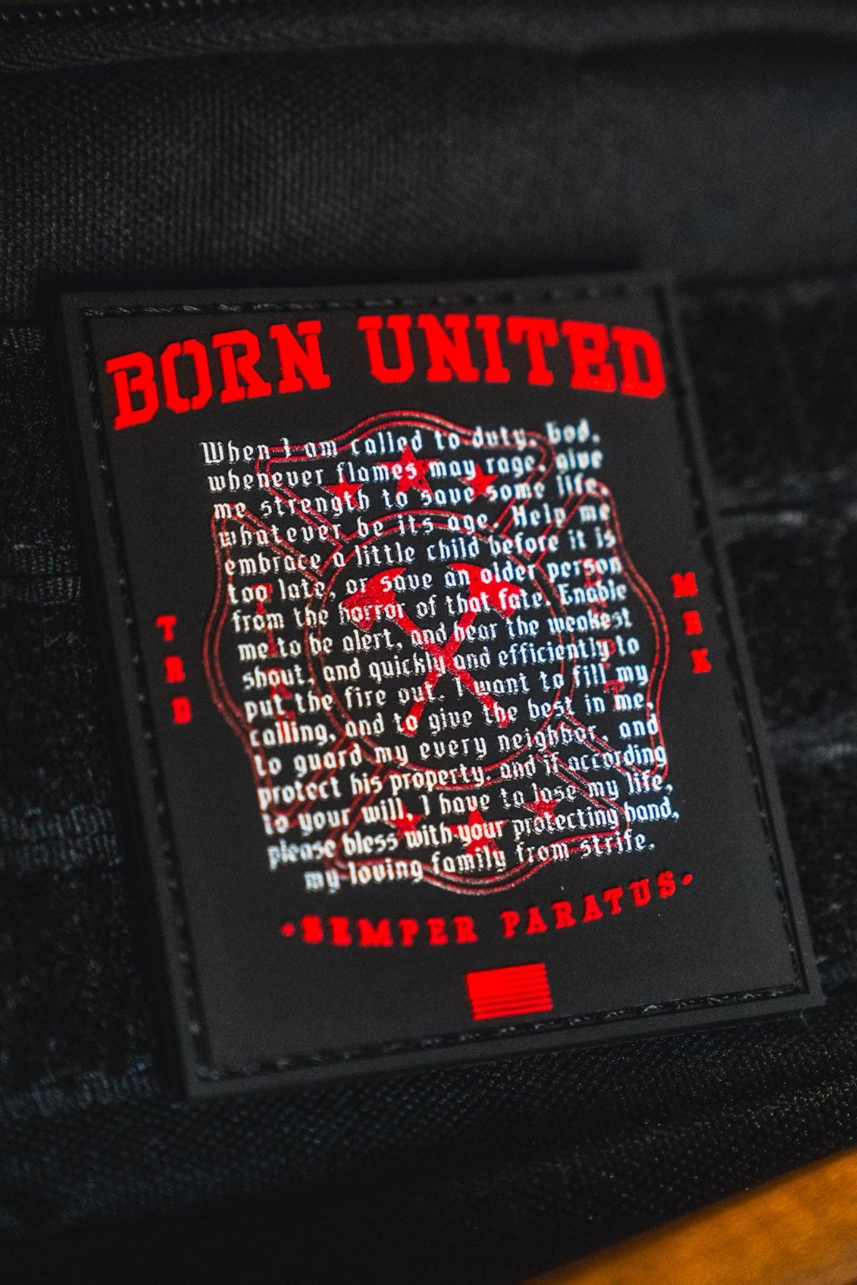 The Fireman's Prayer PVC Patch by Born United Private Label features a black Velcro backing and displays striking red and white text that reads BORN UNITED, followed by an inspiring pledge about duty, bravery, and protection. The phrase SEMPER PARATUS appears at the bottom. Measuring 3 inches, this patch is perfect for making a bold statement on your gear.