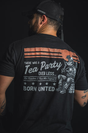 A man wearing the Born United Private Label “Tea Party” black cap and T-shirt, featuring a graphic that reads: “There was a Tea Party over less. For freedom & those who defend it. Born United,” with an illustration of a soldier—a bold nod to the spirit of the historic tea party and an homage to those who defend liberty.