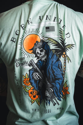 A person wearing the “Always Deadly - Mint” shirt from Born United Private Label, featuring a bold, vibrant mint color with a graphic of a skeleton in tactical gear, sun, palm trees, and the text “BORN UNITED” and “Always Steady.”.
