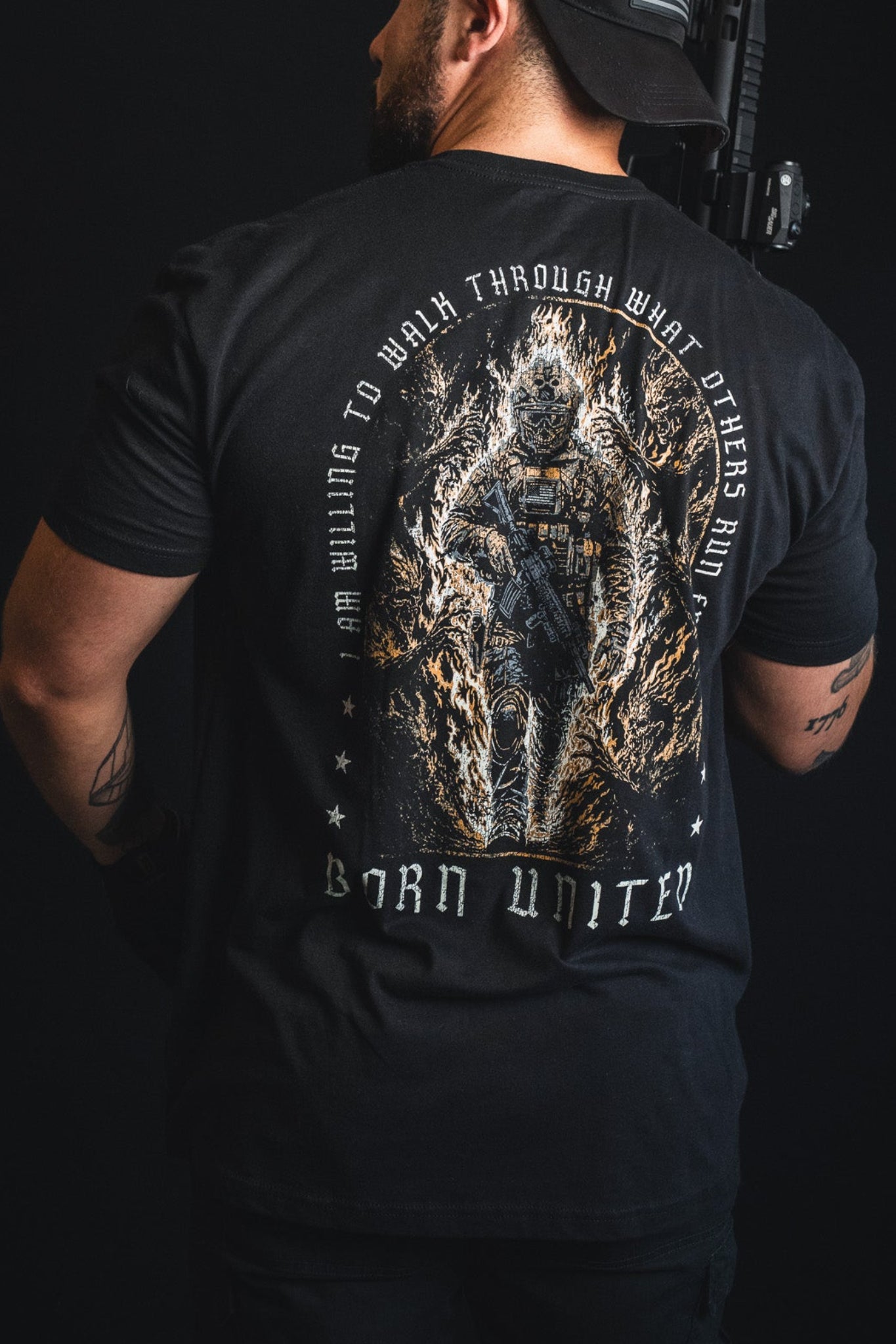 A man wearing the “Walking Through Fire” premium quality t-shirt by Born United Private Label, featuring a striking graphic of a soldier surrounded by flames and the powerful text “I am willing to walk through what others run from. Born United.” This resilience shirt is designed to embody inner strength and courage—ideal for those who face challenges head-on.