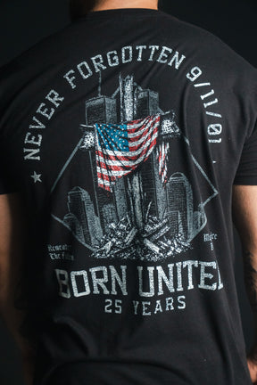 A person wearing the “We Remember: 25th Anniversary” black remembrance tee by Born United Private Label, featuring an illustration of the Twin Towers, an American flag, and the text Never Forgotten 9/11/01, Born United—a powerful September 11 memorial symbolizing honor and resilience.
