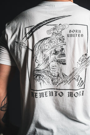 A person wearing the Memento Mori - White t-shirt from Born United Private Label, featuring a bold graphic of a grim reaper with a scythe and the text “Born United” and “Memento Mori” on the back—an eye-catching design that embraces philosophical reflections on mortality.