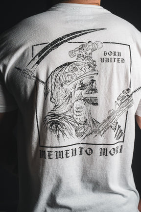 A person wearing the Memento Mori - White t-shirt from Born United Private Label, featuring a detailed skeletal graphic with “Born United” above and “Memento Mori” below—a philosophical reminder of our shared mortality.