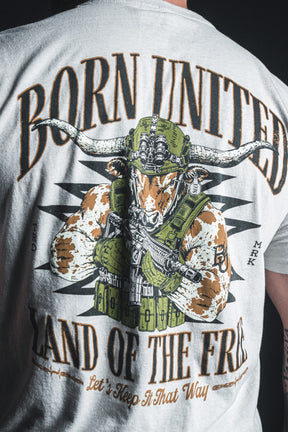 Wearing the “Freedom Frontier” shirt from Born United Private Label, a person sports an illustration of an armed longhorn in tactical gear along with the words “Born United, Land of the Free, Let’s Keep It That Way”—a bold statement of patriotism and American values.