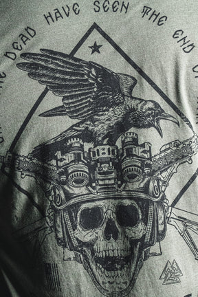 A black graphic on gray fabric features a crow perched atop a skull wearing night vision goggles, encircled by partial text inspired by a George Santayana war quote; this design is titled “Only the Dead” from the Born United Private Label.