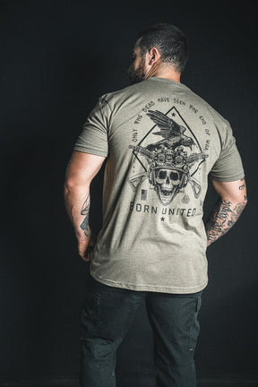 A man stands with his back to the camera, wearing the “Only the Dead” T-shirt from Born United Private Label, which features a striking design of a skull, eagle, and guns alongside George Santayana’s iconic quote—“Only the dead have seen the end of war”—and bold “Born United” text.