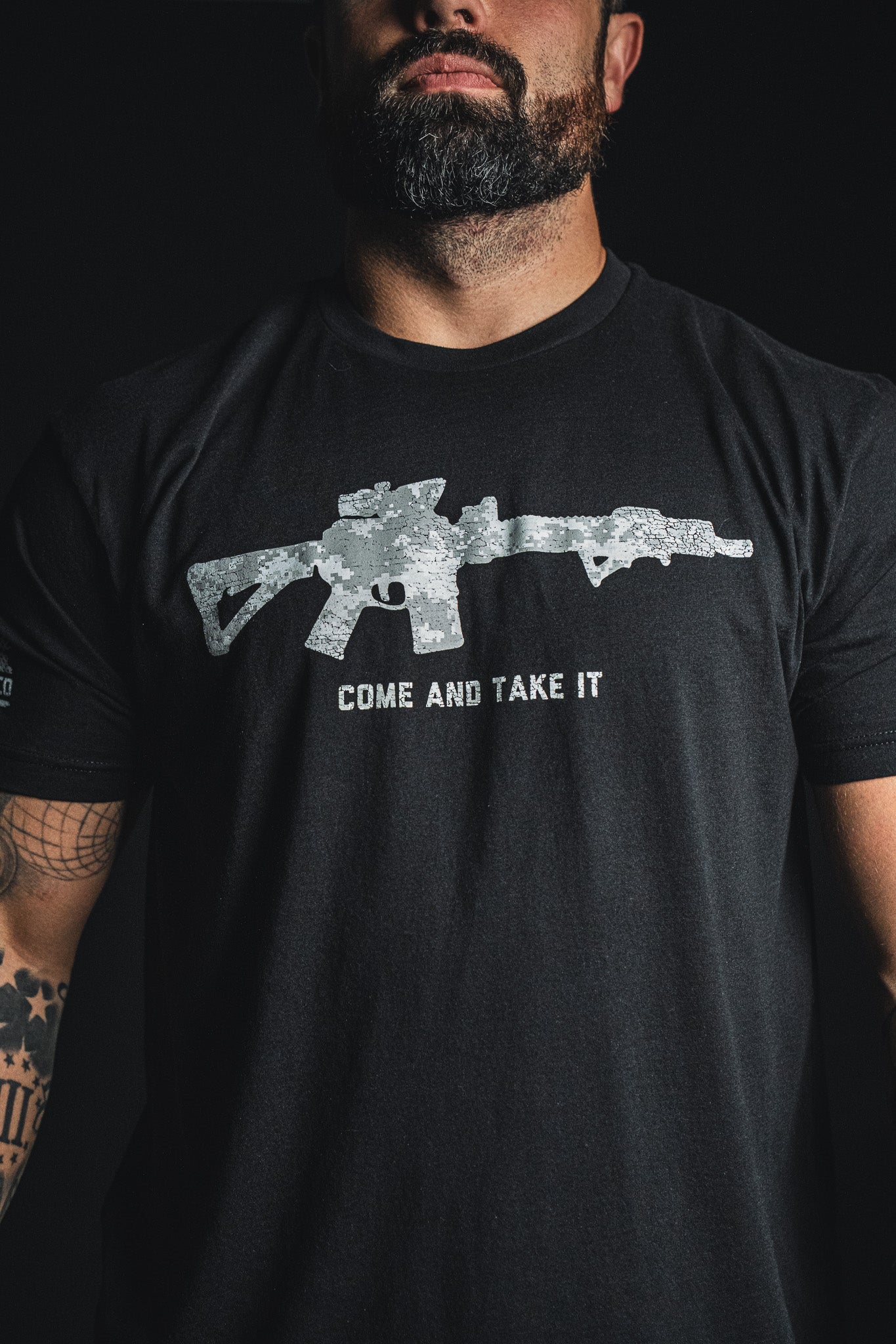 A man wearing the Born United Private Label “Come and Take It” black tee, which features a graphic of a rifle with the bold text “COME AND TAKE IT” printed below—a statement piece for 2nd Amendment pride.