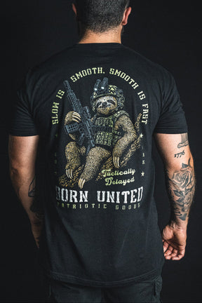 Back view of a person wearing a Tactically Delayed Tee, featuring a graphic of a sloth in tactical gear holding a rifle with the text Slow is smooth, smooth is fast.