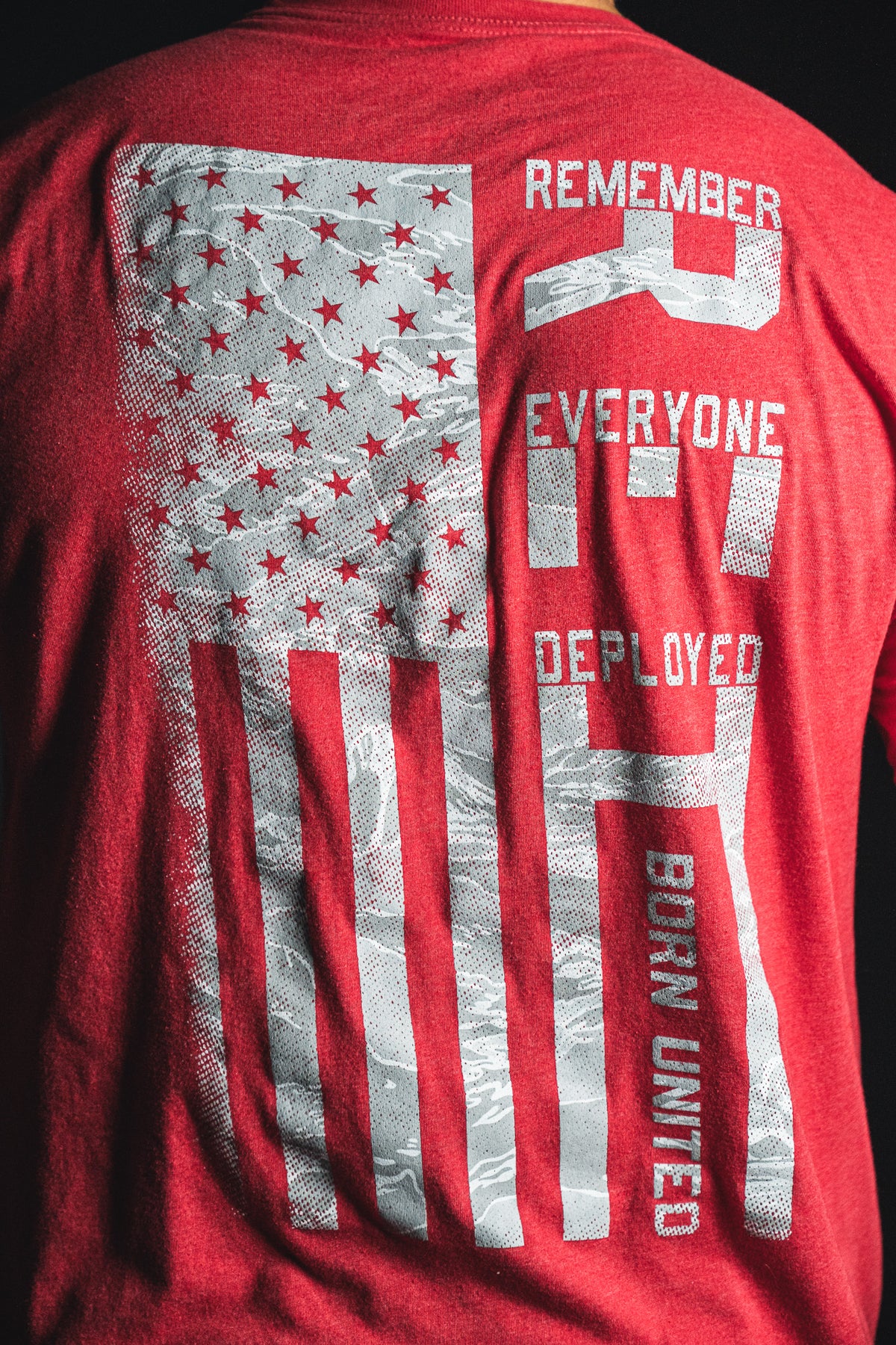 Back of a red Born United Private Label RFV2 shirt featuring a stylized American flag and the text “Remember Everyone Deployed V2 Born United” in white letters.