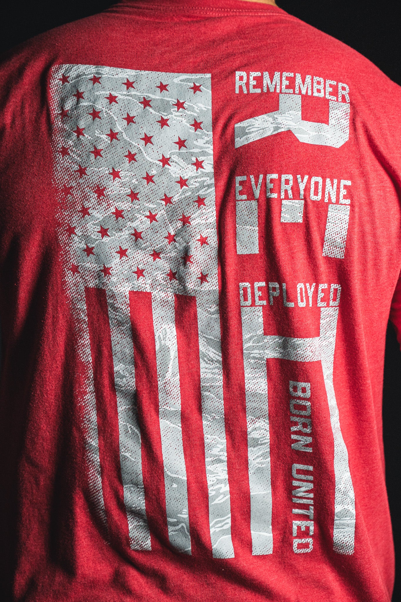 Back of a red Born United Private Label RFV2 shirt featuring a stylized American flag and the text “Remember Everyone Deployed V2 Born United” in white letters.
